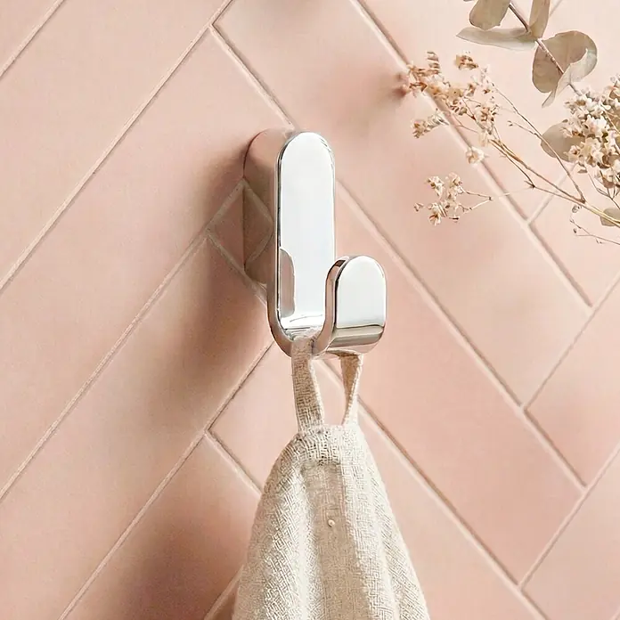 Lenz Aura Handtuchhaken - 1-armig, Verchromt - Glänzender silberner Kleiderhaken an rosa Fliesenwand, hält helles Handtuch.