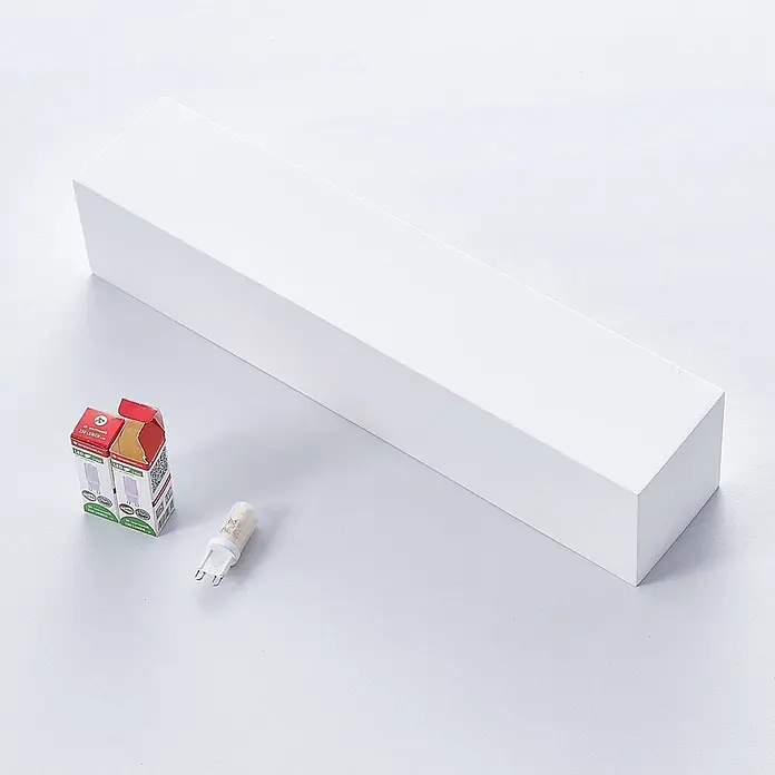 Lindby Wandleuchte Santino - L x B x H: 7,5 x 35,3 x 7,5 cm, weiß / opal, G9 - Weißes rechteckiges Leuchtengehäuse mit einer G9 LED-Birne und ihrer Verpackung.