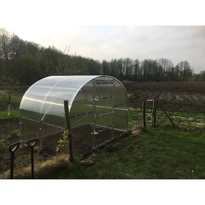 Klasika Greenhouses Gewächshaus Baltic Lt Klasika - Außenmaß inkl. Dachüberstand (B x T): 300 x 200 cm, Material Seitenwand: Kunststoff, 4 mm, Silbergrau - Bogenförmiges Polycarbonat-Gewächshaus mit silbernem Metallrahmen, im Freien an einem Acker, bereit zum Gärtnern.