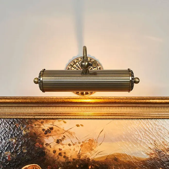 Lindby Wandleuchte Joely - bronze / altmessing, bronze / altmessing, E14 - Messing-Bilderleuchte, die den oberen Teil eines gerahmten Gemäldes beleuchtet.