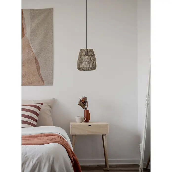 PR Home Pendelleuchte Saigon - 25 W, E27 - Geflochtene Pendelleuchte mit Naturfaserschirm, über einem Holznachttisch in gemütlichem Schlafzimmer.