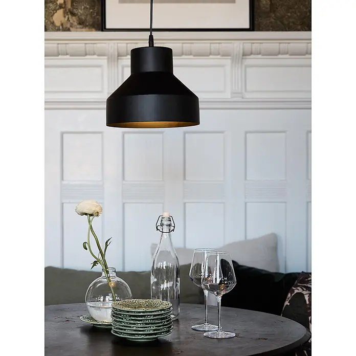 PR Home Pendelleuchte Solo - 25 W, E27 - Schwarze Pendelleuchte mit goldenem Interieur hängt über einem gedeckten Esstisch und spendet Licht.