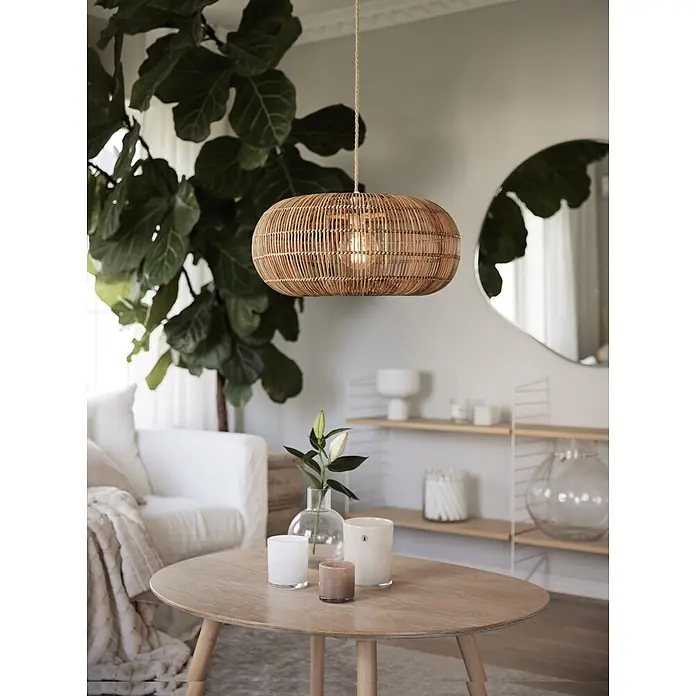 PR Home Pendelleuchte Rattan - 15 W, E27 - Eine längliche Hängeleuchte aus geflochtenem Rattan hängt von der Decke und beleuchtet ein modernes Wohnzimmer.