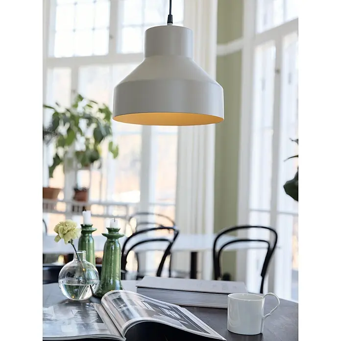 PR Home Pendelleuchte Solo - 15 W, E27 - Hellgraue Pendelleuchte mit warmgoldener Innenseite, die einen Tisch mit Büchern beleuchtet.