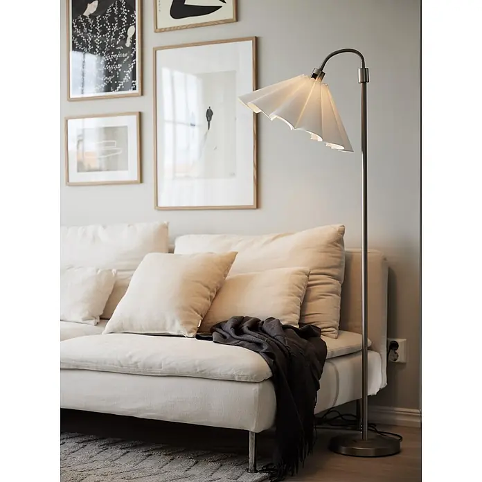 PR Home Pendelleuchte Freja - 15 W - Silberne Stehlampe mit weißem Plisseeschirm und flexiblem Hals, neben einem hellen Sofa stehend.