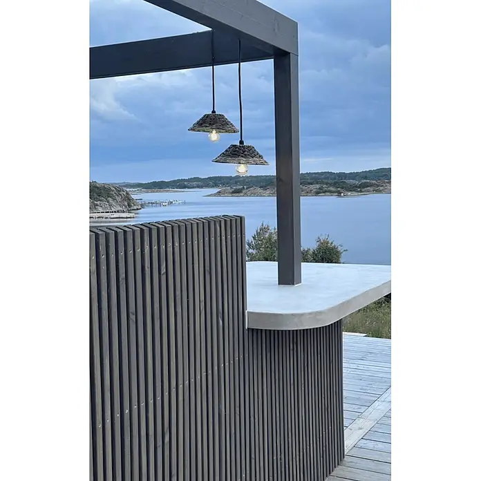 PR Home Pendelleuchte 27cm Outdoor - 40 W, E27 - Zwei Outdoor-Hängelampen mit Korbschirmen beleuchten eine dunkle Holzpergola und Theke mit Blick auf eine Wasserlandschaft.