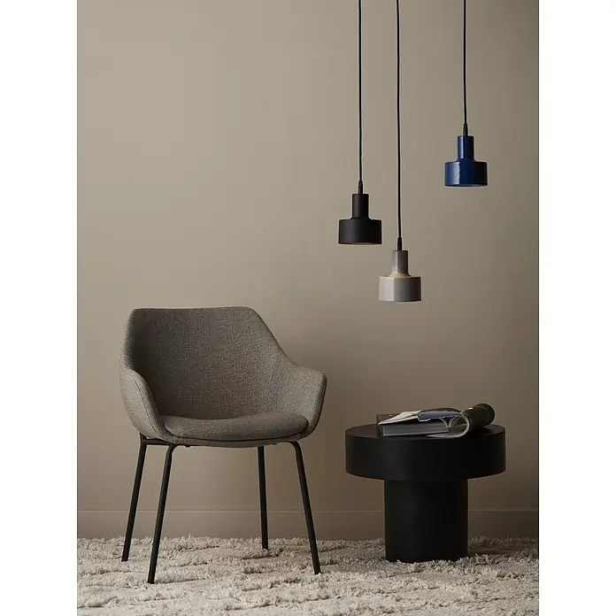 PR Home Pendelleuchte Solo - 25 W, E27 - Drei zylindrische Pendelleuchten in Schwarz, Grau und Blau hängen über einem schwarzen Beistelltisch und einem grauen Stuhl.