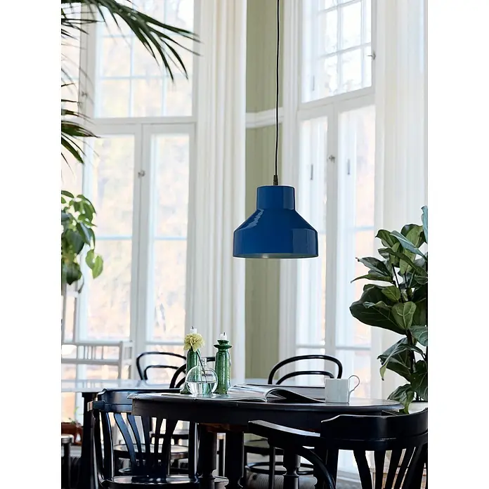 PR Home Pendelleuchte Solo - 25 W, E27 - Eine leuchtend blaue Pendelleuchte hängt mittig über einem dunklen Esstisch und beleuchtet den einladenden Raum.