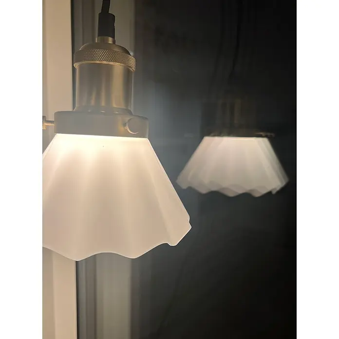 PR Home Pendelleuchte Fensterleuchte - 15 W, E27 - Moderne Pendelleuchte mit weißem geriffeltem Glasschirm und Messingfassung, im Hintergrund eine verschwommene Reflexion.