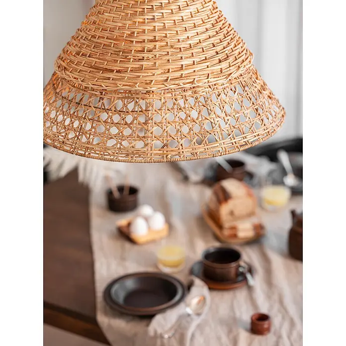 PR Home Pendelleuchte Pune - 25 W, L x B x H: 50 x 50 x 34 cm, E27 - Geflochtener Rattan-Lampenschirm hängt über einem Tisch mit Frühstücksartikeln.