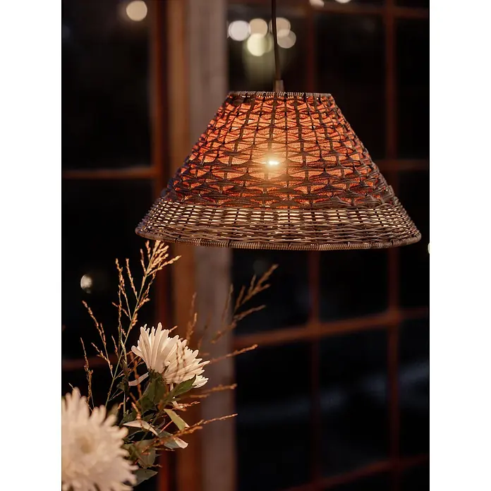 PR Home Pendelleuchte 45cm Outdoor - 40 W, L x B x H: 45 x 45 x 22 cm, E27 - Beleuchtete Pendelleuchte aus Rattan mit warmem Licht, hängt in gemütlicher Innenumgebung über Blumen.