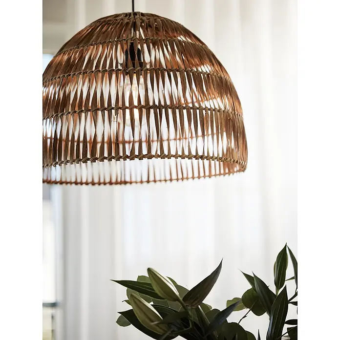 PR Home Pendelleuchte Lace - 40 W, E27 - Braune geflochtene Rattan-Pendelleuchte mit beleuchteter Glühbirne, über grünen Blättern hängend.