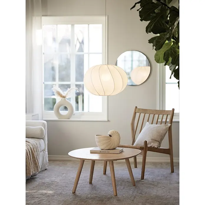 PR Home Pendelleuchte Olivia - 15 W, E27 - Weiße Stoff-Pendelleuchte, kugelförmig mit Rippen, hängt in einem hellen Wohnzimmer über einem Couchtisch.