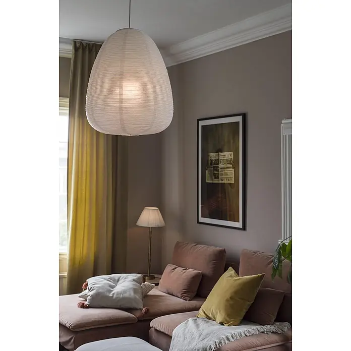 PR Home Pendelleuchte Lampenschirm -  - Große, ovale, gerippte weiße Papierpendelleuchte hängt in einem gemütlichen Wohnzimmer über einem Sofa.