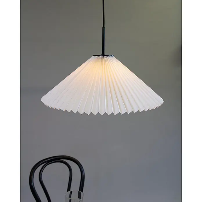 PR Home Pendelleuchte Polly - 25 W, E27 - Eine beleuchtete, plissierte Pendelleuchte aus weißem Papier hängt an einer schwarzen Stange und strahlt ein warmes Licht aus.
