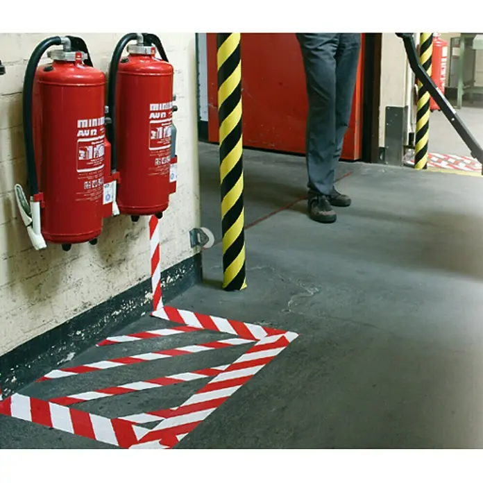 Tesa Cinta de señalización Signal Universal rojo y blanco - An x L: 50 mm x 66 m, Rojo/Blanco - Dos extintores rojos cuelgan de una pared, con marcas de seguridad a rayas rojas y blancas en el suelo debajo.