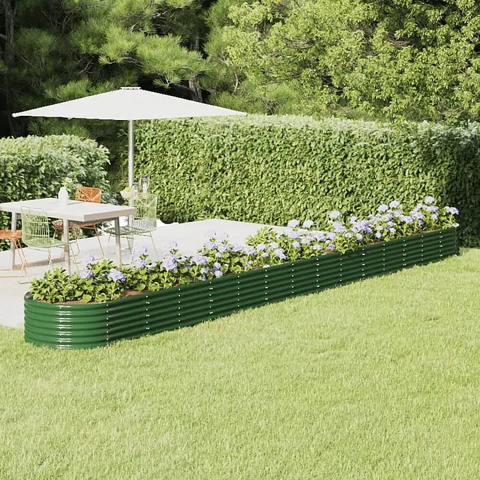 Furnicato Hochbeet - 620 x 80 x 36 cm, Stahl, Grün - Ein langes, grünes Wellblech-Hochbeet mit lila Blumen, auf einem Rasen neben einer Terrasse.