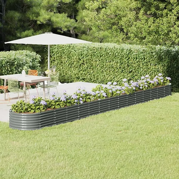 Furnicato Hochbeet oval aus verzinktem Stahl, Grau -  - Langes, dunkelgraues Hochbeet aus Wellblech, gefüllt mit lila Blumen, trennt Terrasse und Rasen.