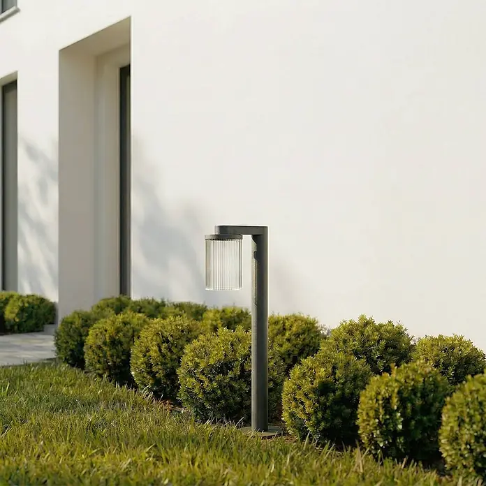 Lucande Außenlaterne Beelia -  - Moderne dunkelgraue Außenpollerleuchte mit gerilltem Glasschirm, beleuchtet einen Gartenweg.