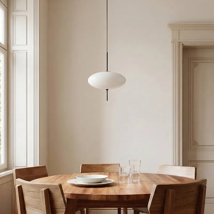Lindby Pendelleuchte Hikari - weiß / opal, Schwarz, weiß, E14 - Weiße ovale Pendelleuchte mit schwarzem Stiel hängt über einem Holzesstisch.