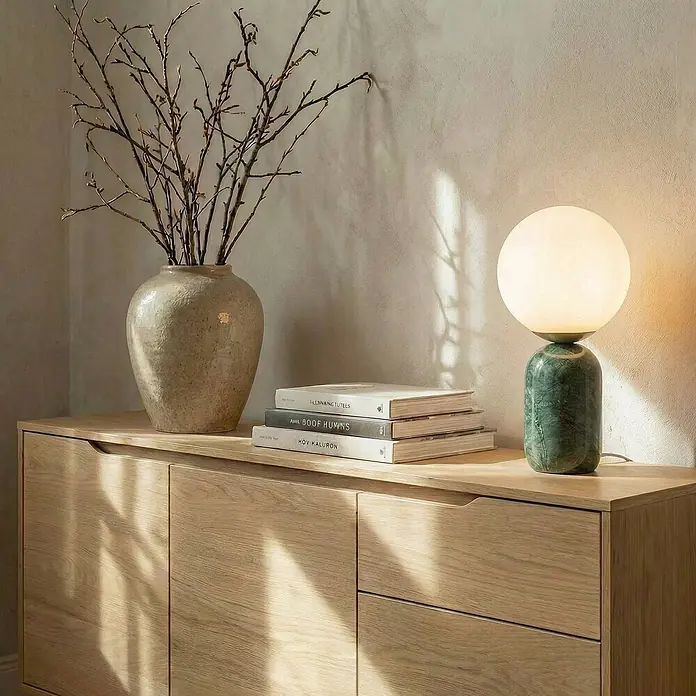 Lindby Tischleuchte Lennes - grün, weiß / opal, E27 - Eine stilvolle Tischlampe mit kugelförmigem weißem Diffusor und grünem, marmoriertem Zylinderfuß, beleuchtet ein helles Holzmöbel.