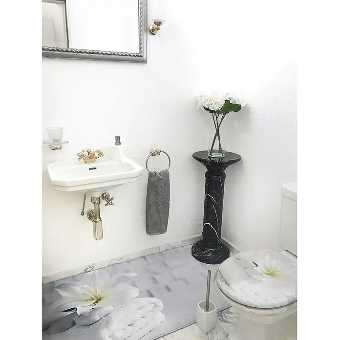 SANILO WC-Sitz Good Feeling - MDF, Weiß, Ohne Absenkautomatik - Elegantes Badezimmer mit einem weißen Wandwaschbecken, WC mit Blumenmuster, schwarzem Podest und einer floralen Badematte mit Handtüchern.