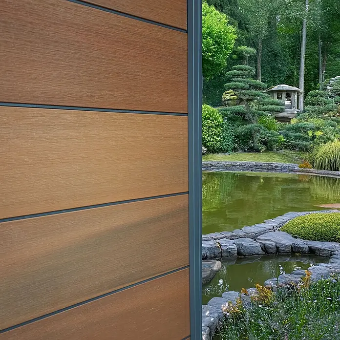 GartenLand Steckzaun-Element Ameland Exclusive Co-extrudiert - Mahagoni, Verbundwerkstoff - Strukturierte Holzoptik-Fassadenplatten in einer Gartenumgebung.