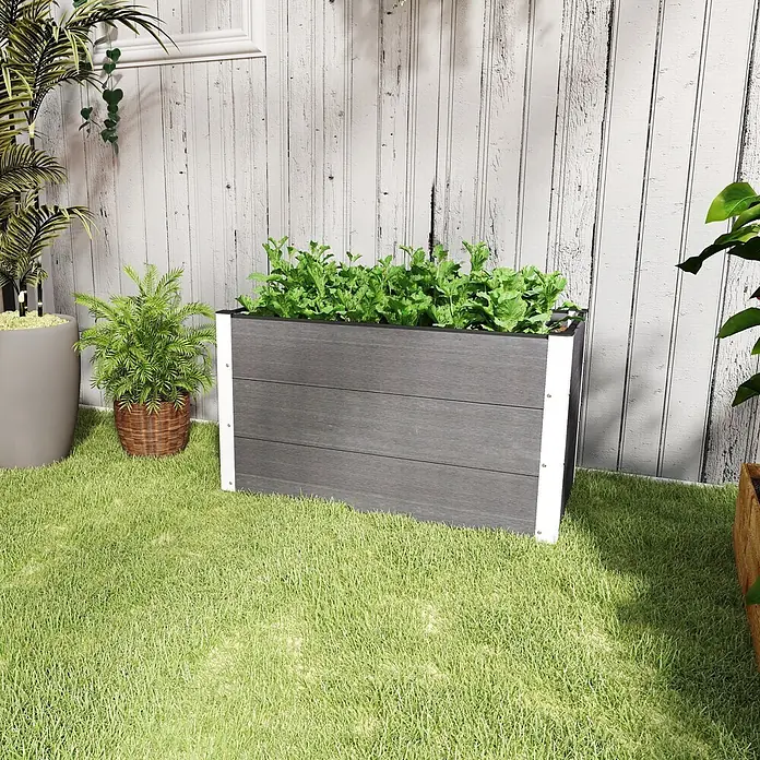 Furnicato Hochbeet - 100 x 50 x 55,5 cm, Verbundwerkstoff, Grau - Rechteckiger Pflanzkasten in dunklem Holz-Look mit weißen Akzenten, bepflanzt mit Grün, auf Gras im Garten.