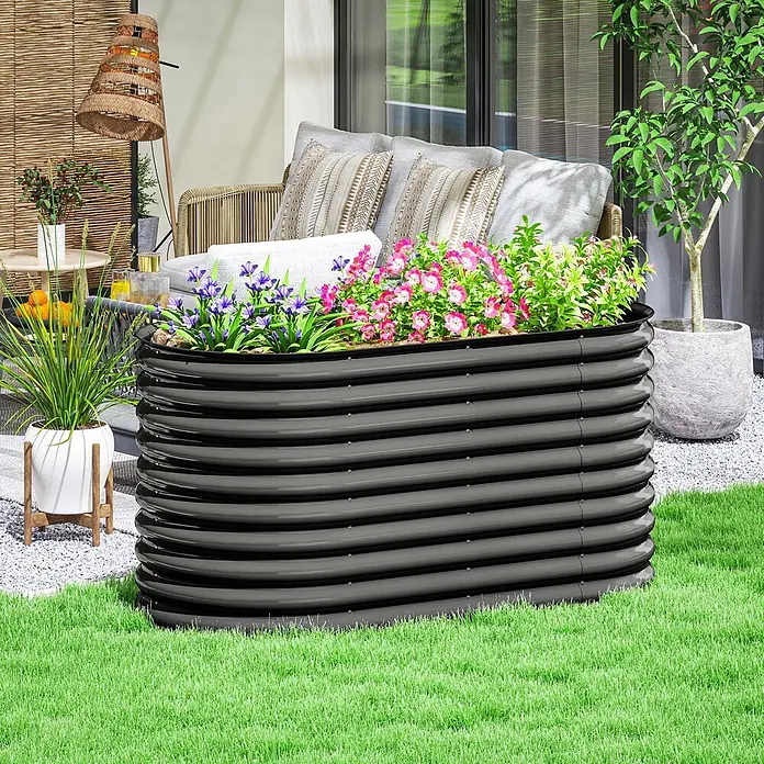 SONNENH Hochbeet Stapelbares - Stahl, dunkelgrau - Ein dunkelgraues, gewelltes Hochbeet aus Metall mit bunten rosa und lila Blumen auf einem Rasen neben einer Terrasse.