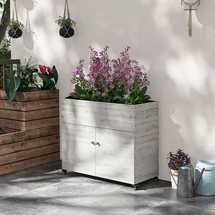 Outsunny Kräuterhochbeet - Material: Holz - Verwitterter weißer Holz-Pflanzkasten auf Rollen mit zwei Türen, gefüllt mit lila Blumen, im Außenbereich.