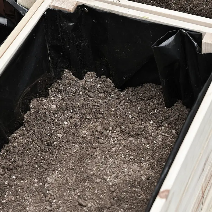 Outsunny Kräuterhochbeet - Material: Holz - Schwarze Folie in einem Hochbeet, teilweise mit Erde gefüllt und am Holzrahmen befestigt.