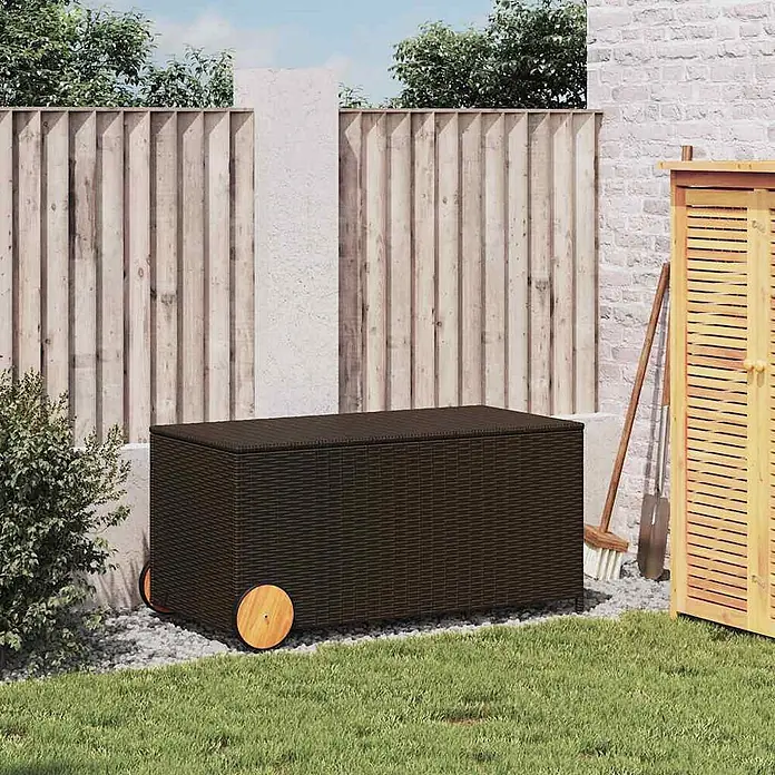 Furnicato Garten-Aufbewahrungsbox - Braun, Naturmaterialien - Dunkelbraune Rattan-Aufbewahrungsbox mit Holzrädern, in einem Garten gezeigt.