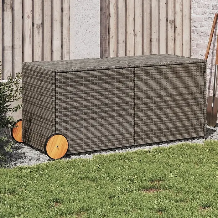 Furnicato Garten-Aufbewahrungsbox - Grau, Naturmaterialien - Grau-braune Rattan-Gartenbox mit Holzrädern, auf Kies neben grünem Gras.