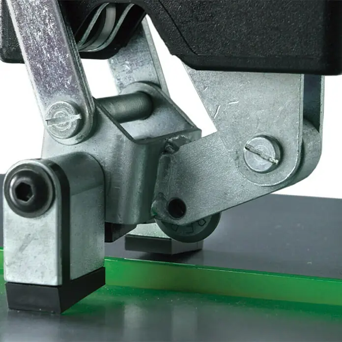 Berg Handfliesenschneider BTC 640 - Max. Schnittlänge: 640 mm, Max. Fliesenstärke: 20 mm - Nahaufnahme eines Fliesenschneiders mit Metallrahmen und schwarzem Griff, der auf einer grünen Fliese steht.