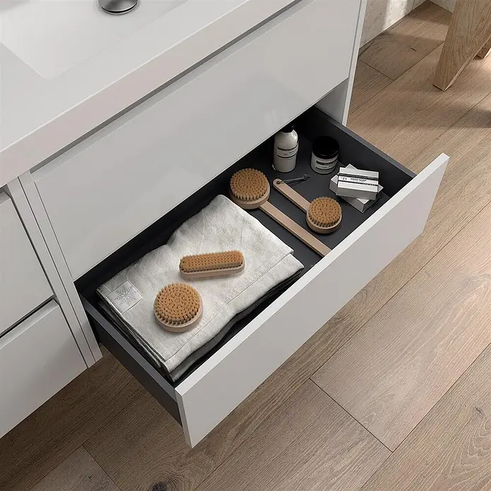 Salgar Badmöbel-Set Salgar - Gesamtbreite Badmöbel: 45 cm, White Satin - Ein offenes weißes Waschbeckenschubfach mit dunklem Innenraum, ordentlich bestückt mit Holzbürsten, gefalteten Handtüchern und Pflegeprodukten.