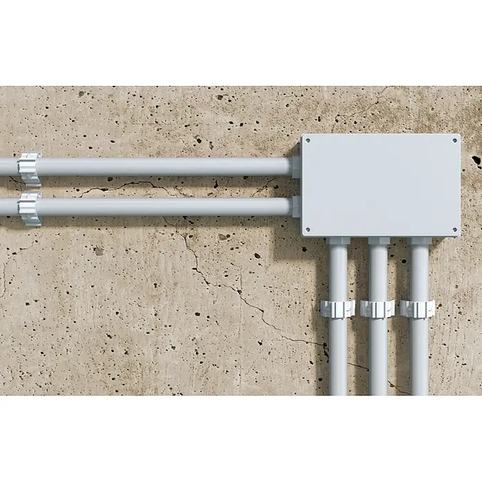 Fischer Klemmschelle Verschlussclip SCN - 25 mm, 100 Stk. - Hellgraue Kunststoff-Elektroinstallation mit Leitungsrohren und Verteilerkasten an einer rissigen Betonwand.