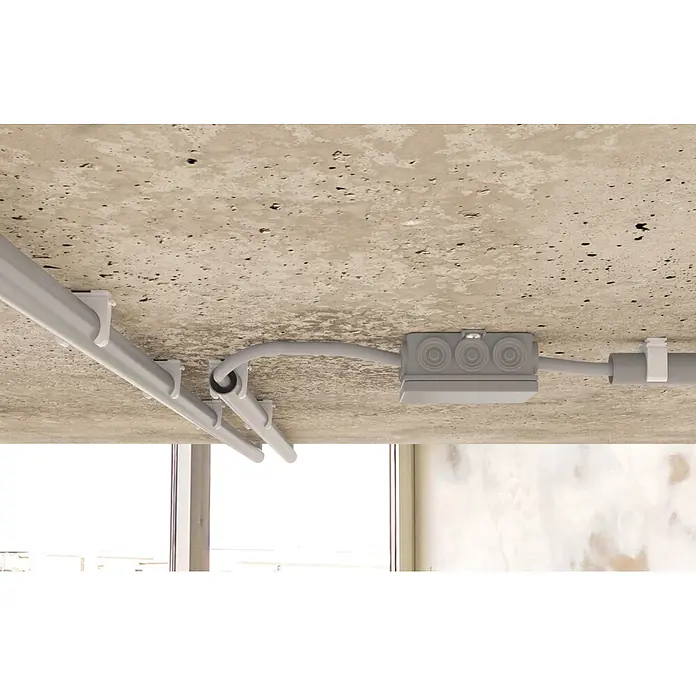 Fischer Klemmschelle Rohrclip Steckfix plus SF RC IEC 16 - 16 mm, 100 Stk. - Graue Kunststoff-Elektroleitungen und eine Abzweigdose an einer Betondecke, die eine sichtbare Elektroinstallation zeigen.