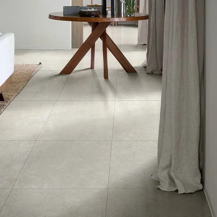 Feinsteinzeugfliese Cortina - 60 x 60 cm, Bianco, Matt - Helle graue quadratische Bodenfliesen mit subtiler Textur, verlegt in einem modernen Interieur.