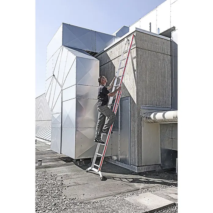 Hymer Anlegeleiter Stufenschiebeleiter 14 Stufen - Anzahl Tritte: 14 Stk., Arbeitshöhe: 7.640 m, Aluminium - Mann klettert auf einer weiß-roten Leiter mit Rollen auf ein Dach, um ein Gebäude zu erreichen.