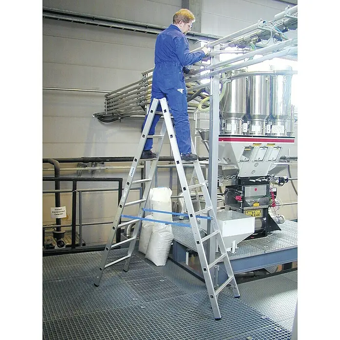 Krause Stabilo Doppelleiter - Anzahl Tritte: 16 Stk., Arbeitshöhe: 3,55 m, Aluminium - Ein Mann steht auf einer KRAUSE Trittleiter, um Wartungsarbeiten an einer industriellen Anlage durchzuführen.