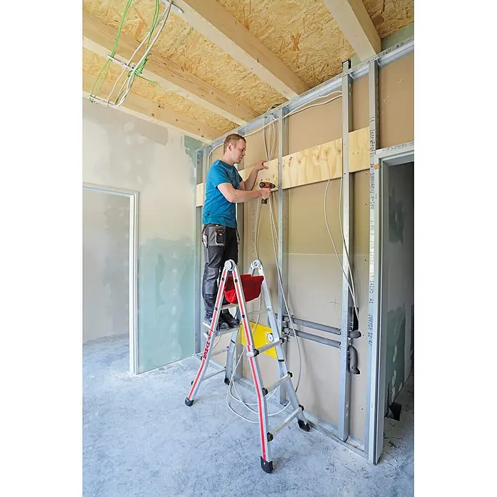 Hymer Teleskopleiter Teleskopleiter Telestep 4x4 Sprossen - Anzahl Tritte: 4 Stk., Arbeitshöhe: 5.000 m, Aluminium - Mann benutzt eine silber-rote Stehleiter für Arbeiten an einer Wand beim Bau.