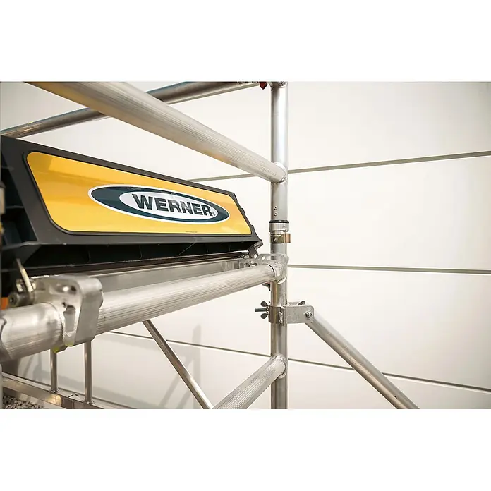 Werner Rollgerüst Klappgerüst Tower 3T nach DIN Norm EN 1004-1 AH 7,55m - Arbeitshöhe: 7.550 m, Belastbarkeit Plattform: 216 kg - Werner Gerüstplattformsegment mit gelb-schwarzem Logo aus silbernem Aluminium, Teil einer Metallgerüstkonstruktion.