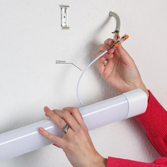 LED's work LED-Feuchtraumlichtleiste - Länge: 60 cm, Lichtfarbe: Neutralweiß, 18 W, IP40 - Person installiert eine weiße lineare LED-Leuchte und verbindet Kabel mit Steckklemmen.