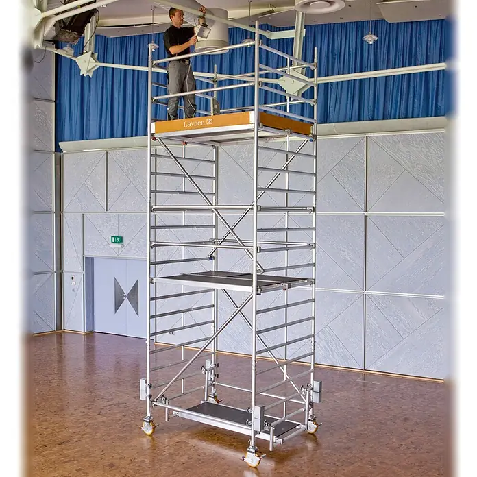Layher Rollgerüst Rollgerüst Uni Kompakt P2 mit Gerüststützen 4,20m AH - Arbeitshöhe: 4.200 m - Mobiles Aluminium-Fahrgerüst (Layher) mit Arbeiter, der eine Deckenleuchte einstellt.