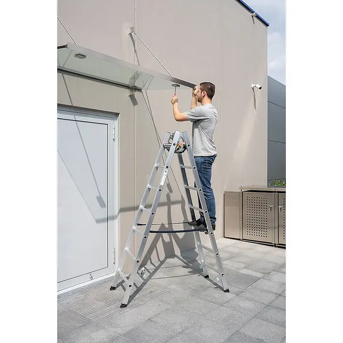 Munk Doppel-Stehleiter Sprossenstehleiter 2x10 Sprossen - Anzahl Tritte: 10 Stk., Arbeitshöhe: 4.200 m, Aluminium - Ein Mann steht auf einer silbernen Aluminiumleiter und montiert ein Glasvordach.