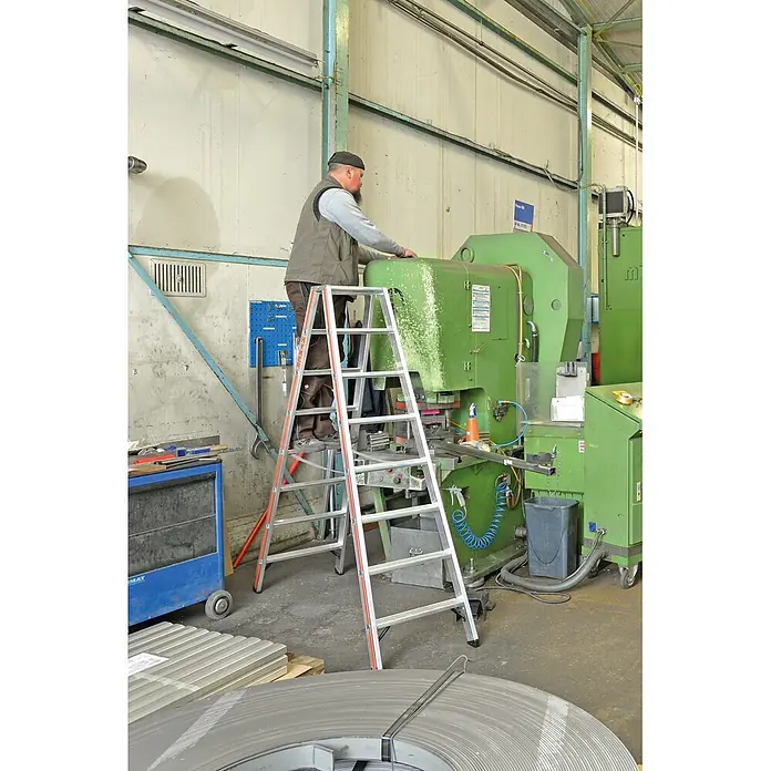 Hymer Stehleiter Stufenstehleiter mit Alu-Druckguss Gelenk 2x3 Stufen - Anzahl Tritte: 3 Stk., Arbeitshöhe: 2.220 m, Belastbarkeit: 150 kg, Aluminium - Mann auf einer Aluminiumleiter mit orangefarbenen Akzenten, der an einer großen grünen Maschine in einer Werkstatt arbeitet.