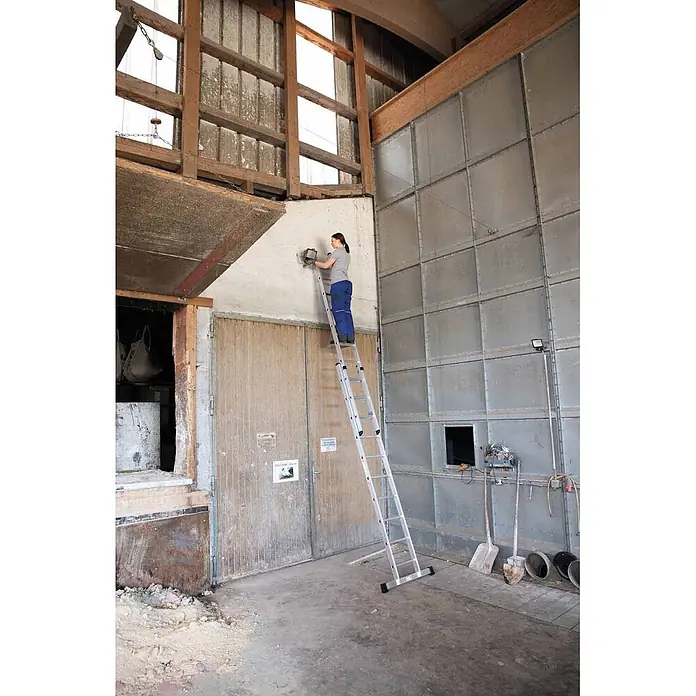 Munk Schiebeleiter Schiebeleiter 2x6 Sprossen - Anzahl Tritte: 6 Stk., Arbeitshöhe: 4.100 m, Aluminium - Silberne Aluminium-Anlegeleiter, die von einer Person zum Arbeiten an einer hohen Wand benutzt wird.
