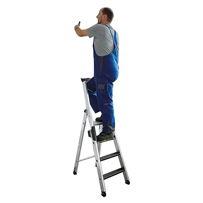 Munk Stehleiter Stehleiter mit clip-step R13 250kg, 3 Stufen - Anzahl Tritte: 3 Stk., Arbeitshöhe: 2.700 m, Aluminium - Silberne Aluminium-Klappleiter mit schwarzen Stufen, ein Mann in blauer Arbeitslatzhose steht darauf und benutzt ein Werkzeug.