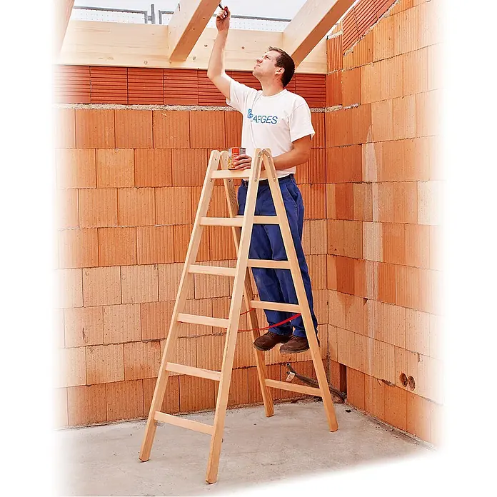 Zarges Stehleiter Holz Stehleiter Cresta B, beidseitig begehbar 2x10 Sprossen - Anzahl Tritte: 10 Stk., Arbeitshöhe: 4.100 m, Holz - Holz-Klappleiter in Gebrauch. Ein Mann streicht Holzbalken an der Decke in einem Rohbau.