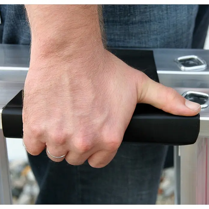 Munk Stehleiter Stehleiter beidseitig begehbar mit relax-step 2x14 Stufen - Anzahl Tritte: 6 Stk., Arbeitshöhe: 2.900 m, Aluminium - Hand hält schwarzen, gepolsterten Griff an einem silbernen Rahmen für komfortables Handling.